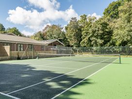 A tennis court with a net and surrounding fence at The Cottage in Wimborne Minster