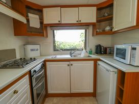 A kitchen with a stove oven sink bread box microwave and small refrigerator at Fron Dderw Caravan Llanfairynghornwy near Llanfechell