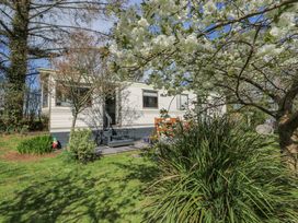 A garden with trees and a caravan with outdoor seating at Fron Dderw Caravan in Llanfairynghornwy near Llanfechell