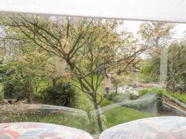 View of a garden with bird feeders and green grass at Fron Dderw Caravan Llanfairynghornwy near Llanfechell