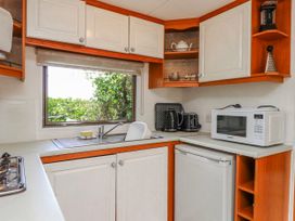 A kitchen with sink and appliances at Fron Dderw Caravan Llanfairynghornwy near Llanfechell