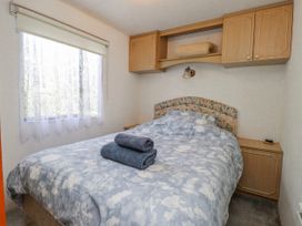 A bedroom with a bed and towels at Fron Dderw Caravan Llanfairynghornwy near Llanfechell