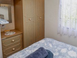 A bedroom with a bed and wardrobe at Fron Dderw Caravan Llanfairynghornwy near Llanfechell