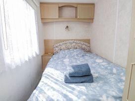 A bedroom with a bed and towels at Fron Dderw Caravan Llanfairynghornwy near Llanfechell