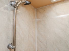 A shower with a shower head and tiled walls at Fron Dderw Caravan Llanfairynghornwy near Llanfechell