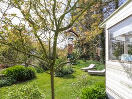 A garden with a tree and bird feeders at Fron Dderw Caravan in Llanfairynghornwy near Llanfechell