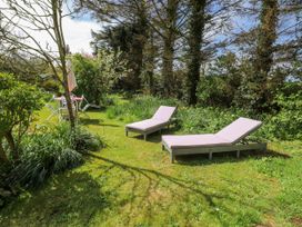 A garden with lounge chairs and an umbrella at Fron Dderw Caravan in Llanfairynghornwy near Llanfechell
