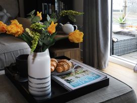A living room with a vase of flowers and croissants on a tray at Apartment 3 in Trearddur Bay