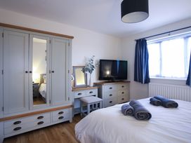 A bedroom with a bed, wardrobe, and television at Apartment 3 in Trearddur Bay