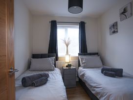 A bedroom with two beds and a nightstand at Apartment 3 Trearddur Bay