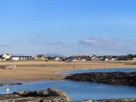 A beach with people walking near water at Apartment 3 Trearddur Bay