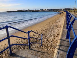 A beach with sand and sea alongside a walkway at Apartment 3 Trearddur Bay