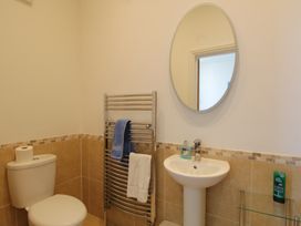 A bathroom with a toilet, a sink, and a mirror at 11 Cove View Apartments in Ilfracombe