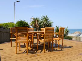 A dining table with wooden chairs on a deck at 11 Cove View Apartments Ilfracombe