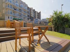 A garden area with wooden furniture and buildings in the background at 11 Cove View Apartments Ilfracombe