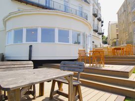 An outdoor area with wooden tables and chairs at 11 Cove View Apartments Ilfracombe