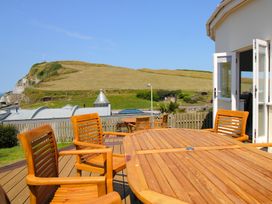 An outdoor patio with wooden furniture at 11 Cove View Apartments in Ilfracombe