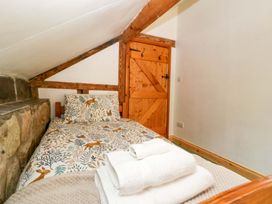 A bedroom with a single bed and a wooden door at Redstart Cottage in Kingsland