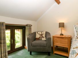 A bedroom with an armchair and bedside table at Redstart Cottage in Kingsland