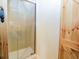 A shower area with a glass door at Redstart Cottage in Kingsland