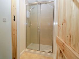 A shower with glass doors and tiles at Redstart Cottage in Kingsland