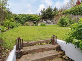 A garden with grass and seating area at Gwynn Cottage in St Mabyn