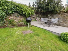 A garden with a barbecue grill and dining table at Gwynn Cottage in St Mabyn
