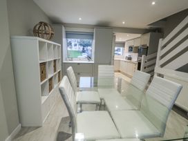 A dining room with a glass table and white chairs at White Sails Y Felinheli