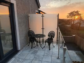 A balcony with two chairs and a table with a glass railing at Escape To The Chapel Anglesey Bryngwran near Rhosneigr