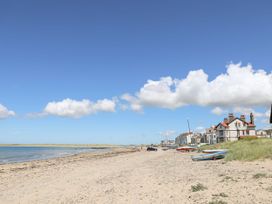 A sandy beach with boats and houses along the shore at Escape To The Chapel Anglesey Bryngwran near Rhosneigr