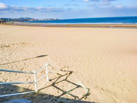A sandy beach with a white railing in the foreground and ocean in the background at The Old Post Office in Llanelian near Old Colwyn