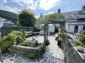 A garden with stone path, plants and seating area at Swn Yr Afon Abergynolwyn near Tywyn