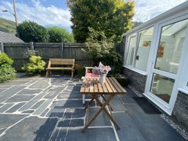 A garden with a table and flowers at Swn Yr Afon in Abergynolwyn near Tywyn