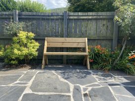 A garden with a wooden bench surrounded by plants at Swn Yr Afon Abergynolwyn near Tywyn
