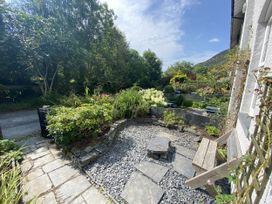 A garden with a stone path and bench at Swn Yr Afon Abergynolwyn near Tywyn