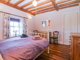 A bedroom with a bed, dresser and chair at Bronfa in Tregarth