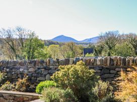 A garden view with a stone wall and mountains in the background at Bronfa in Tregarth