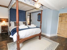 A bedroom with a four-poster bed with folded towels on it two bedside tables with lamps a wooden door and a rug on a wooden floor at Pentre Hall in Bronygarth near Chirk