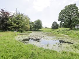 A small pond surrounded by grass and trees at Pentre Hall in Bronygarth near Chirk