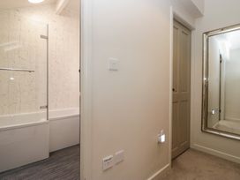 A bathroom with a bathtub and mirror at Cringol Cottage Ambleside