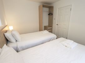 A bedroom with two beds and a wardrobe at 1 Eamont Park in Penrith
