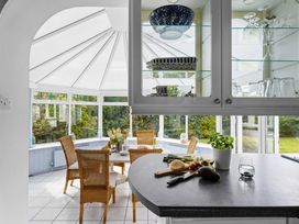 A conservatory with wicker chairs and a table at 7 Duporth Bay in St. Austell