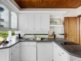A kitchen with cabinets, countertop, sink, and potted plants at 7 Duporth Bay, St. Austell