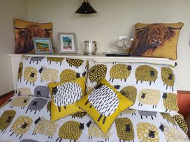 A bedroom with sheep patterned bedding and decorative pillows at The Herdsman Luxury Shepherds Hut in Barnoldswick