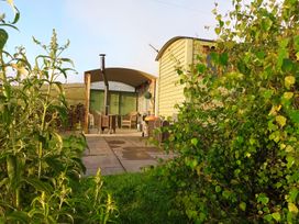 A shepherds hut with outdoor furniture on a patio at The Herdsman Luxury Shepherds Hut in Barnoldswick