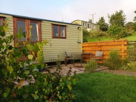 A cabin with a table and chairs outside at The Herdsman Luxury Shepherds Hut in Barnoldswick