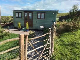 An exterior view of a shepherd's hut with planters and a fence at The Herdsman Luxury Shepherds Hut Barnoldswick