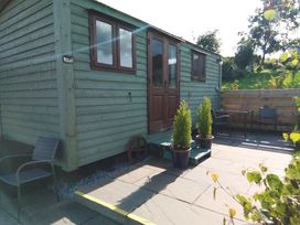 A shepherd's hut with a patio and planters at The Herdsman Luxury Shepherds Hut in Barnoldswick