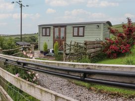 A shepherd's hut with flowers and a fence at The Herdsman Luxury Shepherds Hut in Barnoldswick