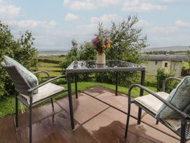 An outdoor seating area with a table and chairs at The Herdsman Luxury Shepherds Hut in Barnoldswick